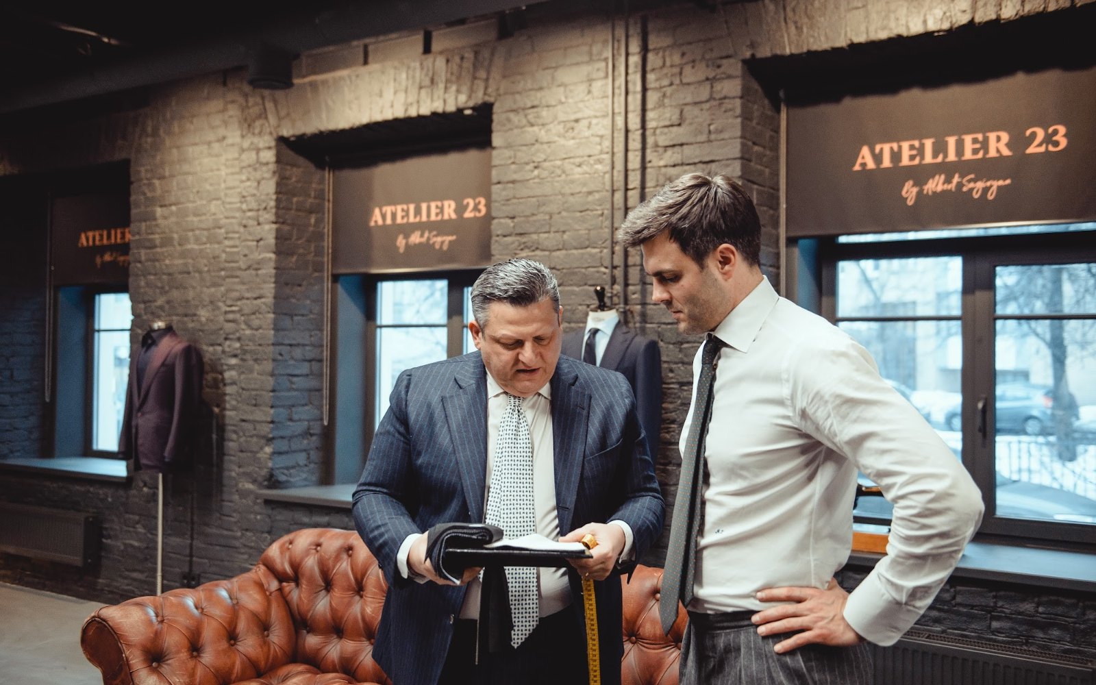 Портной показывает клиенту ткань в ателье ATELIER 23