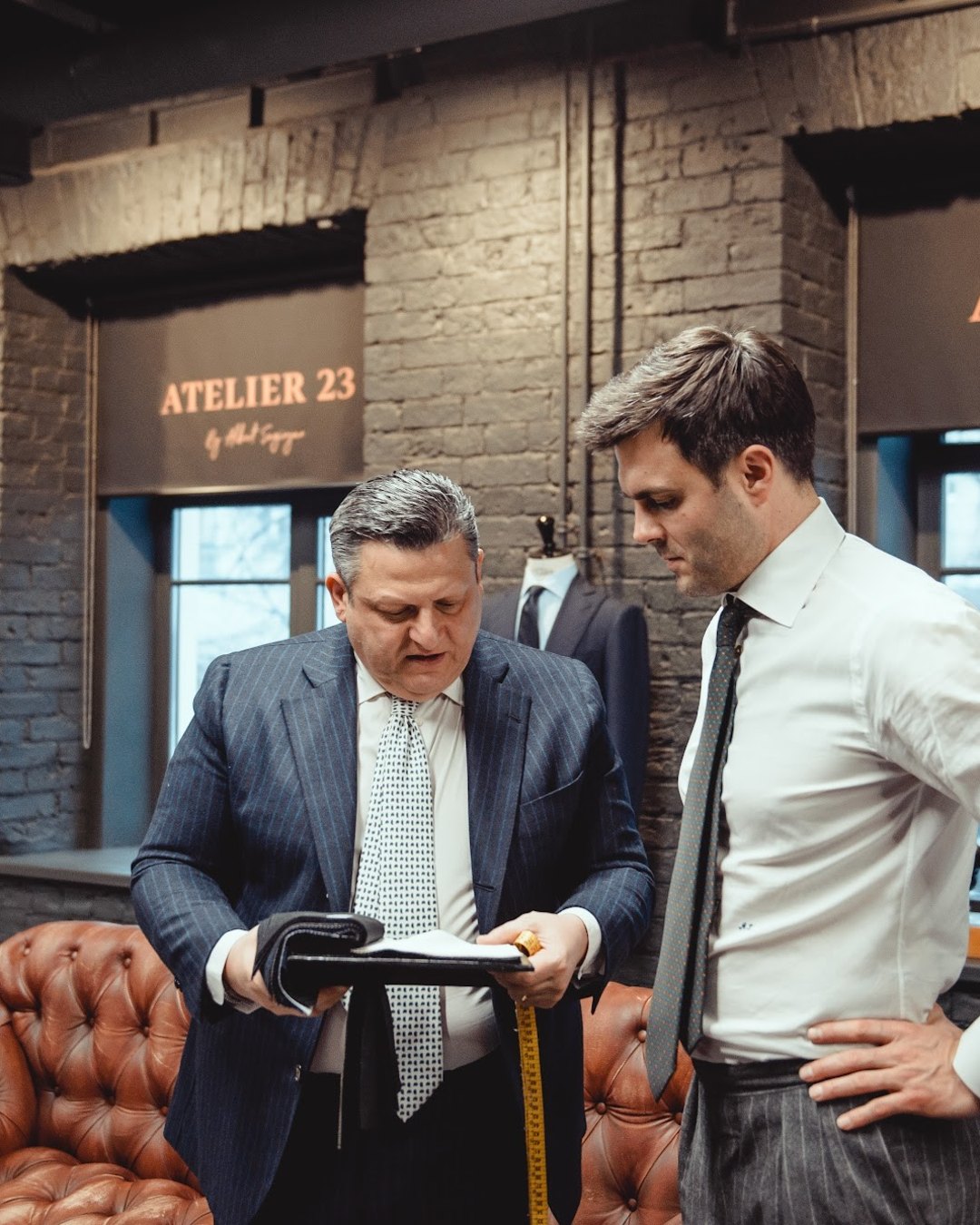 Портной показывает клиенту ткань в ателье ATELIER 23