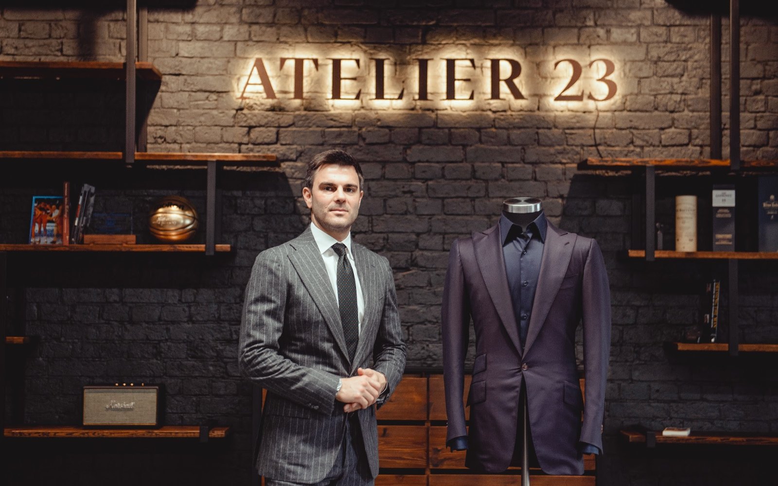 Молодой мужчина в сером костюме в ателье ATELIER 23