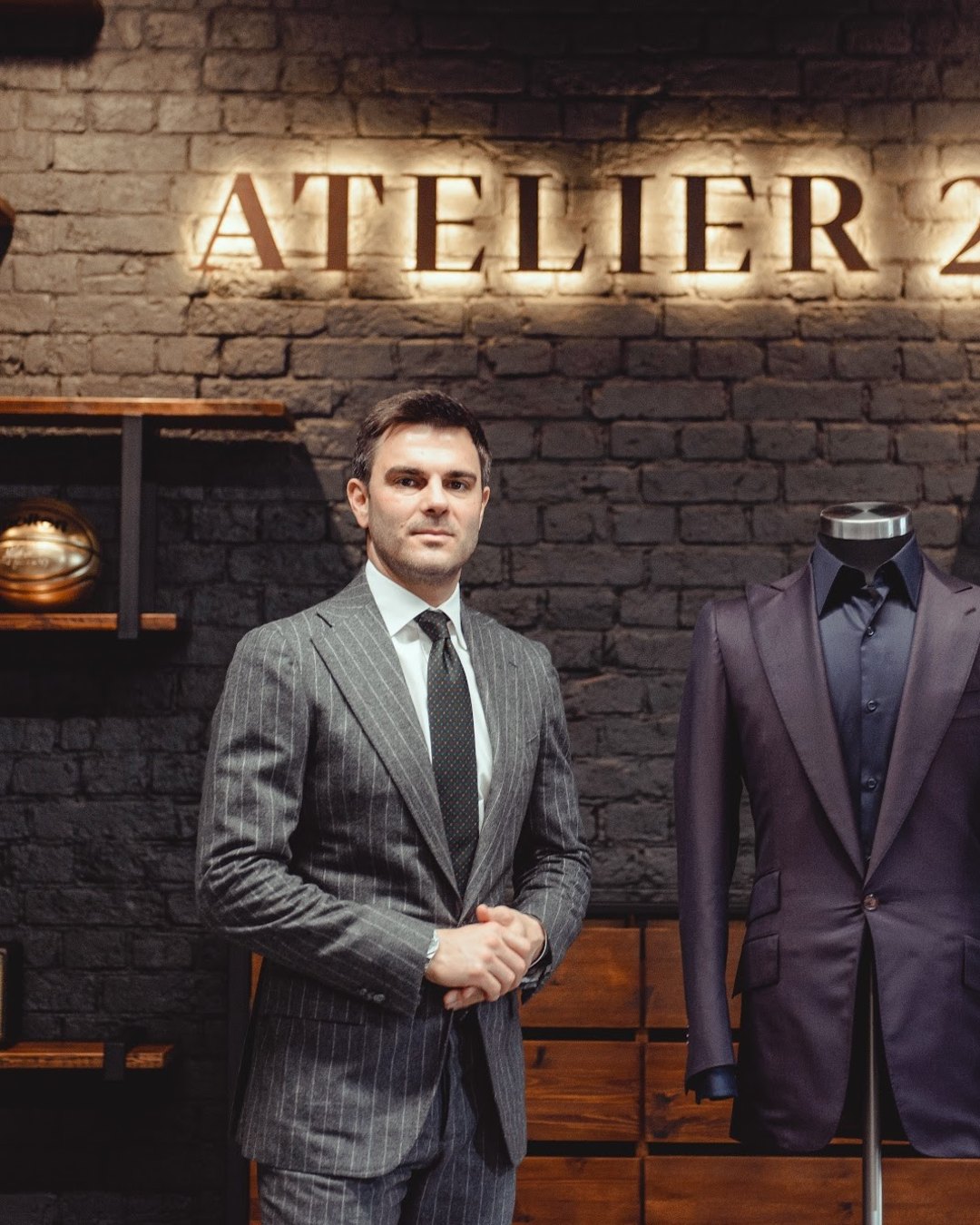 Молодой мужчина в сером костюме в ателье ATELIER 23