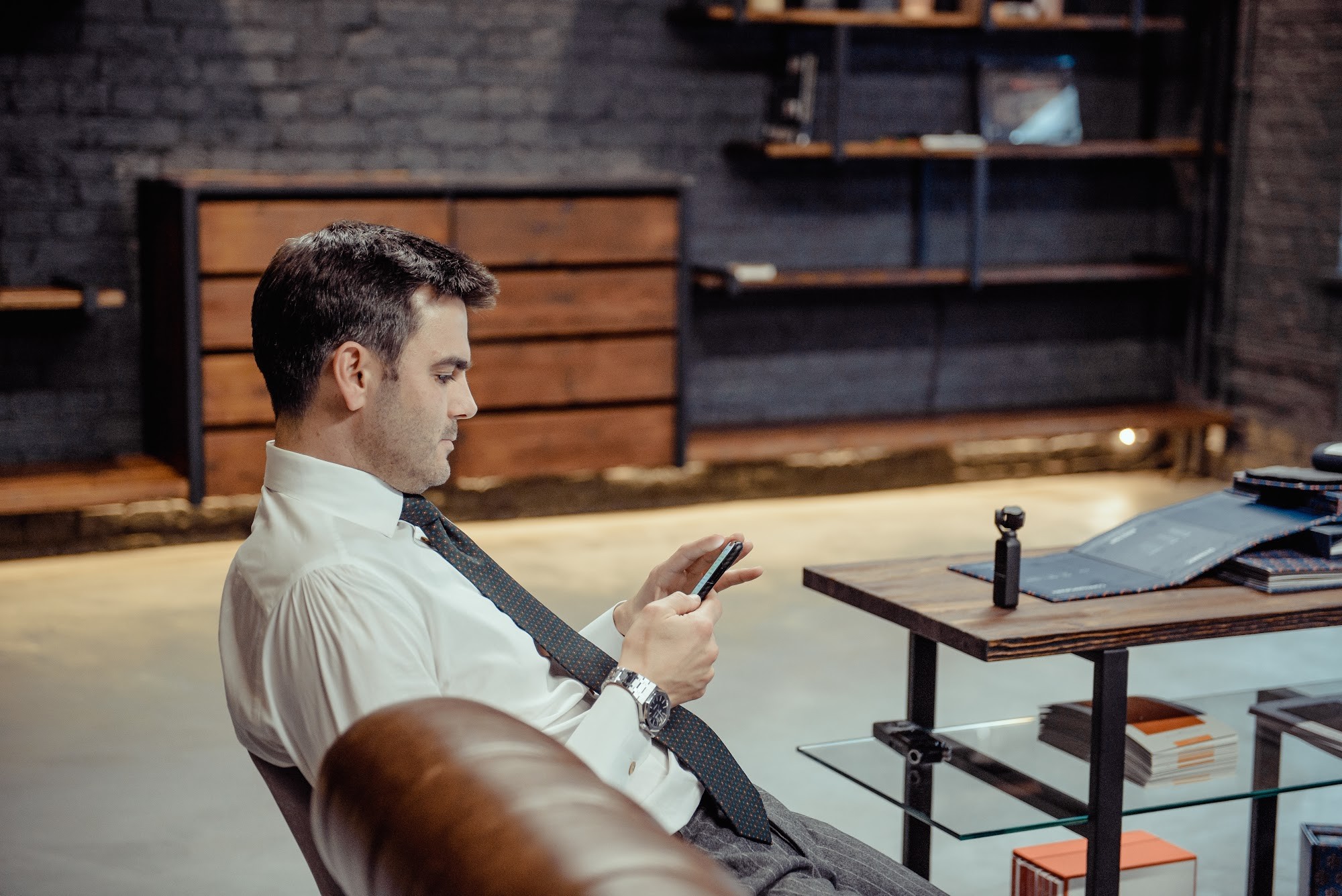 Мужчина в белой рубашке и галстуке сидит на кожаном диване