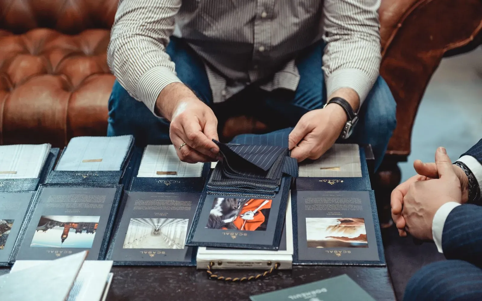 Клиент выбирает ткань по книгам образцов Scabal в ателье ATELIER 23
